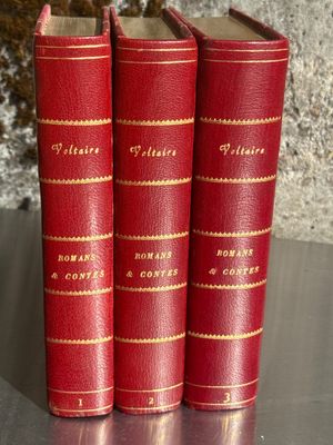 trois livres rouges posés les uns à côté des autres sur une table