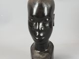 a black sculpture of a man ' s head on a white surface