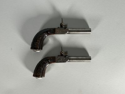 deux pistolets argentés posés sur une surface blanche, sur fond blanc