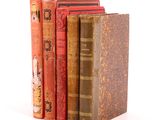 several old books are stacked on top of each other on a white surface