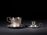 a silver cup and saucer with a saucer on a black surface