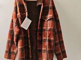 une veste à carreaux orange et marron suspendue à un cintre
