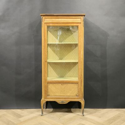 une armoire en bois avec une porte vitrée, posée sur un parquet