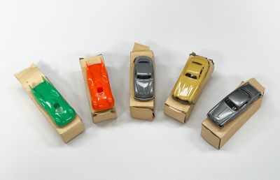 cinq petites voitures miniatures alignées les unes à côté des autres sur une boîte en carton