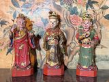 three figurines sitting on a table in front of a wall