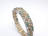 a close up of a gold and turquoise bracelet on a white background