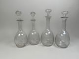three clear glass decanters are lined up against a white background
