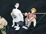 three figurines of people sitting on a black cloth