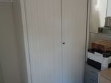 a closet in the corner of a room with a desk and a mirror