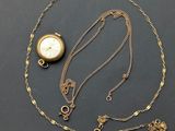 a close up of a gold plated pocket watch and chain on a black surface