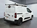 the white van is parked in a large room with a ladder on the roof