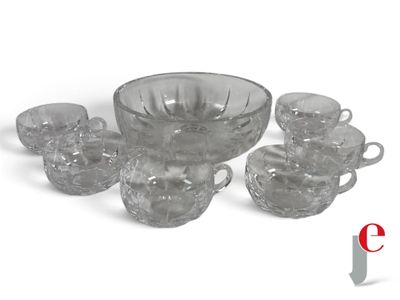 un saladier en verre et des tasses posés sur une surface blanche