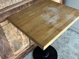 a wooden table with a black base on a carpeted floor