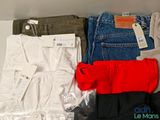 several pairs of pants and a red shirt are sitting on a shelf