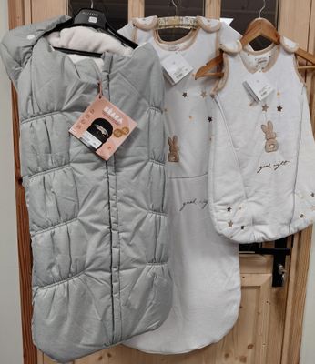 trois vêtements pour bébé suspendus à un portant dans un magasin