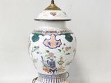 a white and blue vase with a gold base on a table