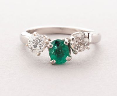 a close up view of a three stone emerald and diamond ring