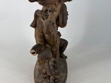 an antique bronze statue of a boy with a bird on a rock