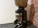 un moulin à café posé par terre près d'un mur de briques