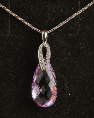 un pendentif en améthyste et diamant posé sur un fond de velours noir