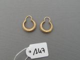 deux paires de boucles d'oreilles créoles en or, avec une étiquette de prix posée sur une surface grise