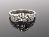 a close up of a diamond engagement ring on a reflective surface
