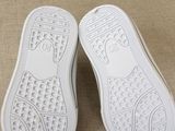 white sneakers with white soles sitting on a beige surface