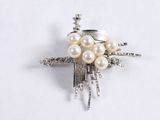 a silver brooch with pearls on it on a white surface