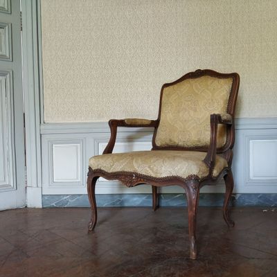 une image représentant une chaise dans une pièce dont l'un des murs est recouvert de papier peint