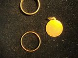 two gold rings and a gold disc on a black surface