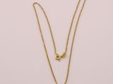 un collier en or avec un pendentif en forme de cœur sur fond blanc