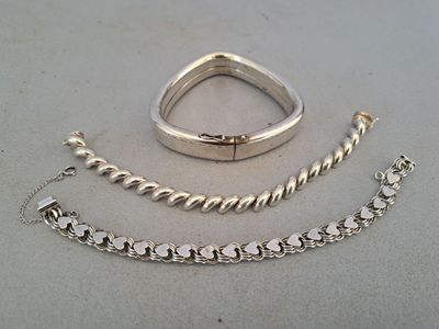 two pieces of silver jewelry sitting on top of a table