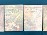 four books are lined up on a blue surface