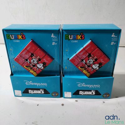 Voici deux boîtes de Rubik's de Disney posées sur une surface blanche.