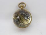 a gold pocket watch with gears inside of it on a white surface