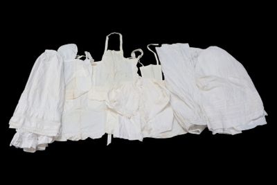 trois robes blanches suspendues à un portant, sur fond noir