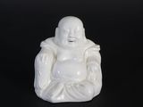 une petite statue de Bouddha blanche posée sur une surface noire
