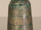 a green glass jar with gold writing on it