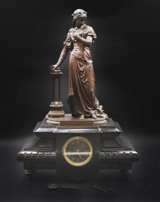 une statue de femme tenant une horloge sur une table
