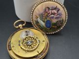 a small gold pocket watch with a picture on it