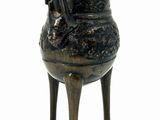 a small bronze pot on a stand with a handle