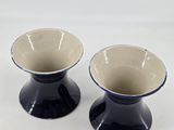 two black and white vases sitting on a white surface