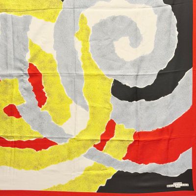 une image représentant une écharpe rouge, jaune et noire ornée d'un motif en spirale