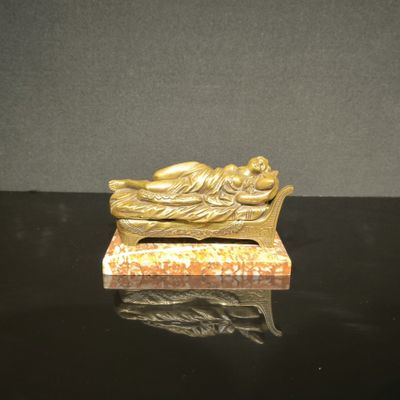 figurine en or représentant une femme endormie sur un banc, posée sur une table noire