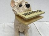 statue of a dog with a book in its mouth sitting on a table