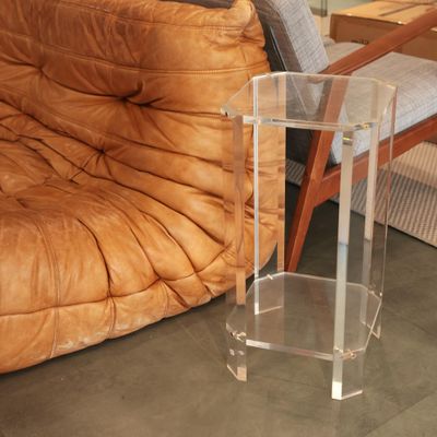 a clear acrylic table on the floor next to a couch