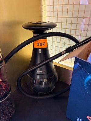 un crochet noir posé sur un comptoir, à côté d'une boîte de grains de café et d'une autre boîte de grains de café