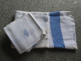 deux serviettes blanches bordées de bleu et ornées d'un monogramme