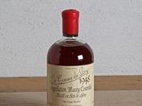 une bouteille d'alcool posée sur une table, avec un mur blanc en arrière-plan