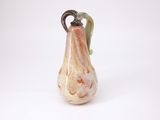 un petit vase en verre muni d'une anse, posé sur une surface blanche